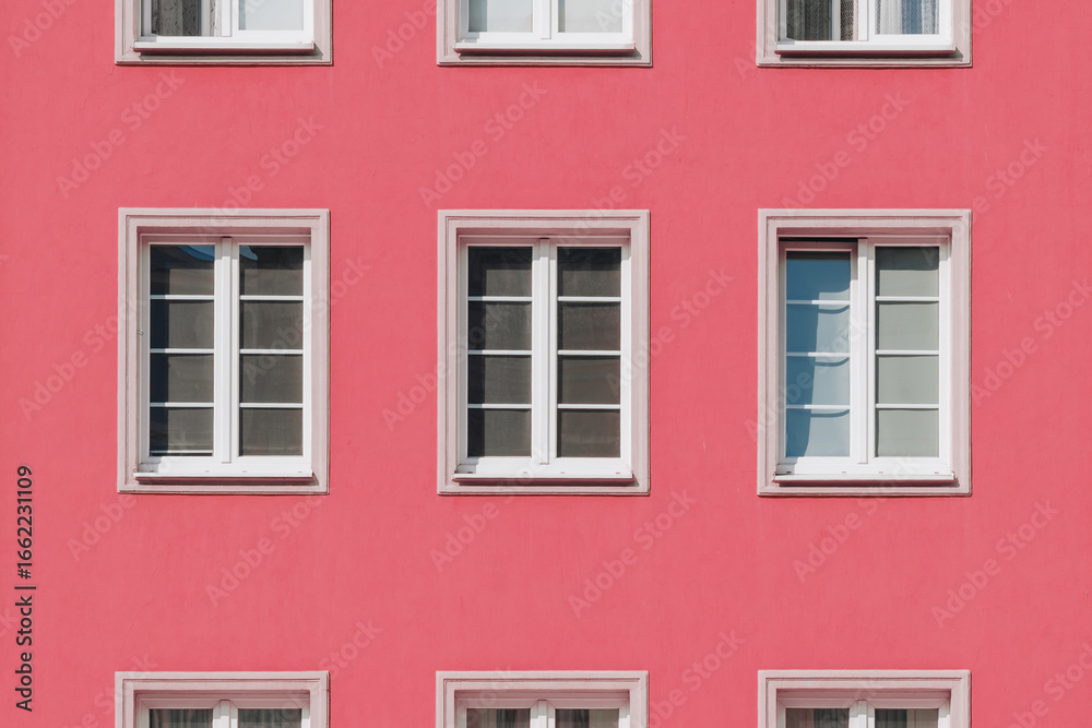 Fototapeta premium Pink Apartment Facade with Symmetrical White Windows