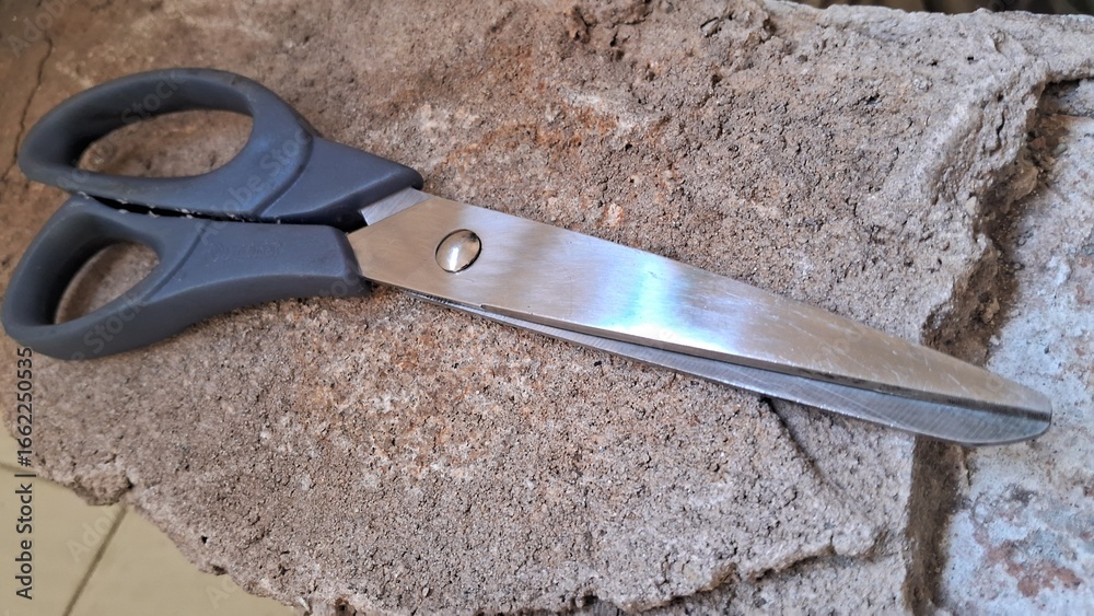 Obraz premium Scissors on a rough textured surface