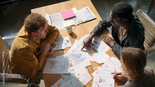 Diverse colleagues gathered around a table, reviewing data charts and graphs during a collaborative business meeting.