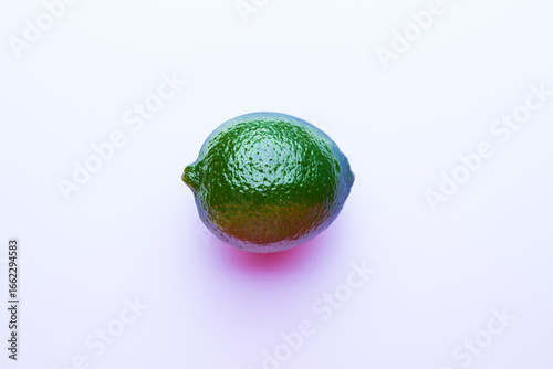 Fresh bright green lime on a pink background.
