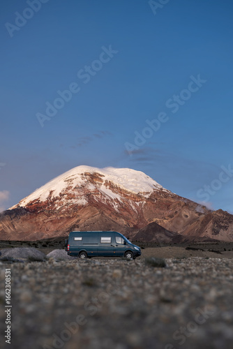 Camper van con el volcán Chimborazo nevado detrás visto con los úlitmos rayos de sol sobre la cumbre