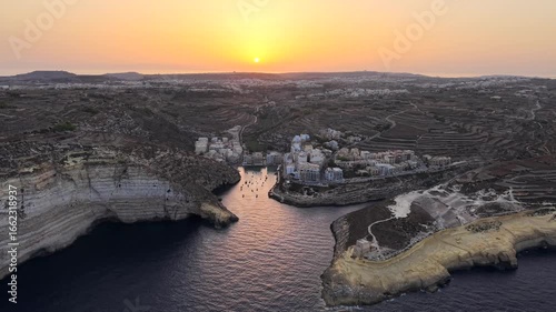 Xlendi Bay, Gozo at sunrise drone video. Aerial footage of the southern coast of the Maltese island at dawn zooming out.