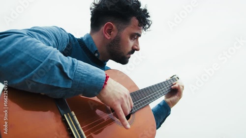 Man Practices Arpeggios on Guitar While Playing Outdoors
