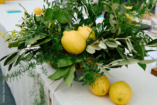 Lemons integrated in green leafy centerpiece on white table