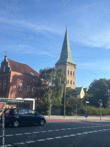Historic Church Tower and City Street Traffic Under Blue Sky