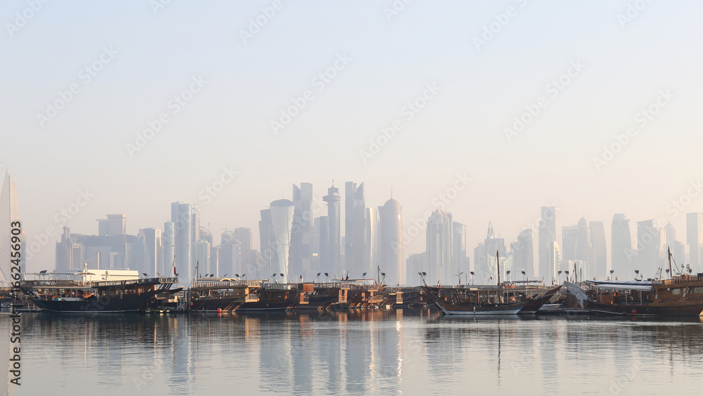 Fototapeta premium カタール・ドーハ コーニッシュの朝の景色 – ダウ船と近代的なスカイライン