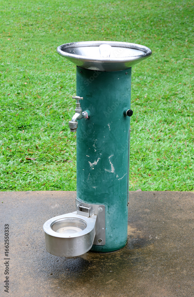 Fototapeta premium Green public water drinking fountain with a dog pet bowl in a park