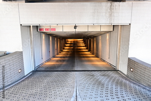 Underground parking ramp glows with warm lights and tiled walls.