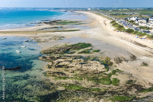 Lorient Morbihan Expansive sandy beach with shallow turquoise sea and rocky formations.