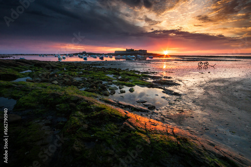 Lorient Morbihan Warm sunset light on a historic coastal fort with rocks and tidal pools.
