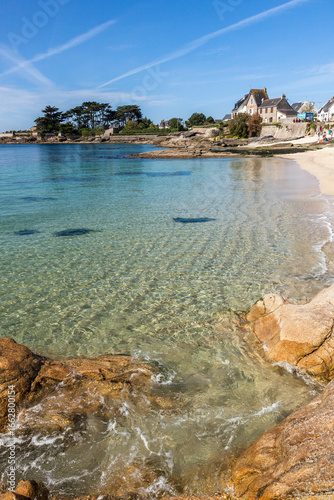 Lorient Morbihan Shallow turquoise water with gentle ripples near a rocky shore and coastal houses.