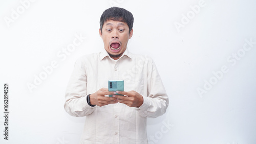 Asian man make a shock face expression when looking to phone that he hold