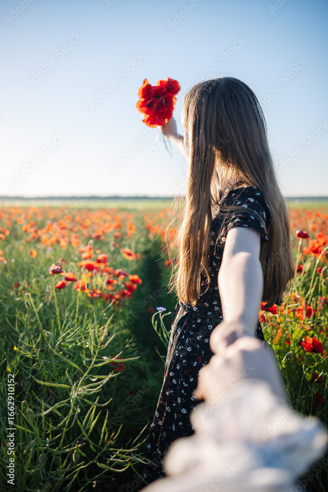 Naklejka premium Romantic couple walking through a poppy field at sunset, enjoying nature and holding hands