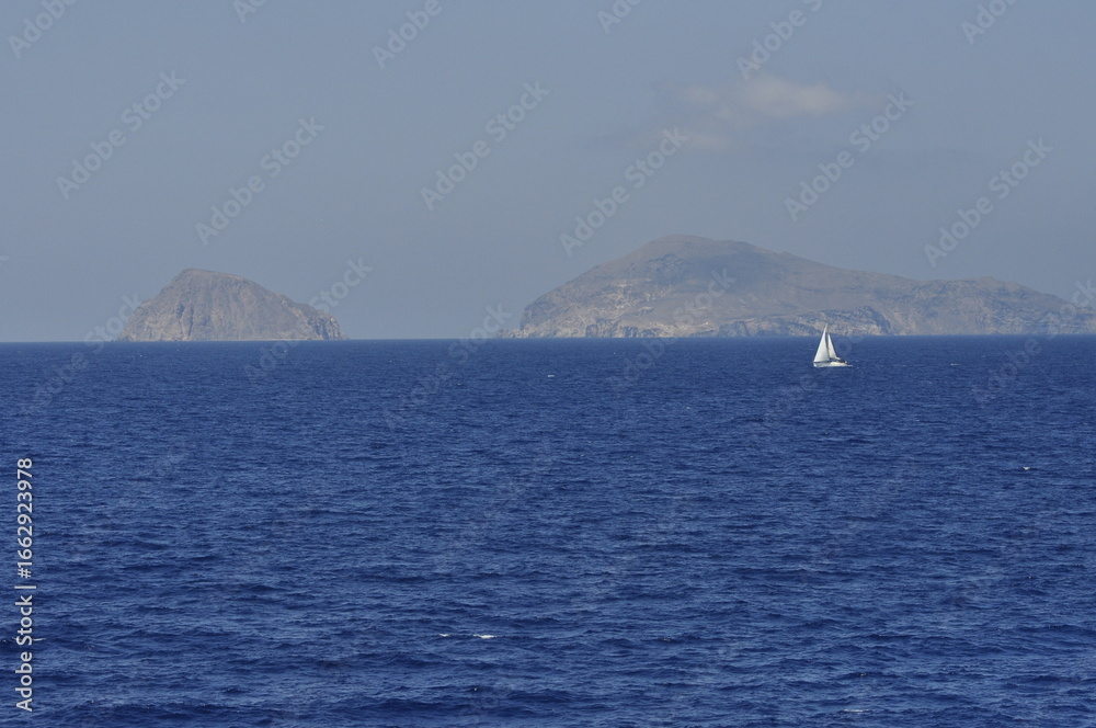 Fototapeta premium A Serene Ocean View Featuring Distant Islands and a Graceful Sailboat in the Distance