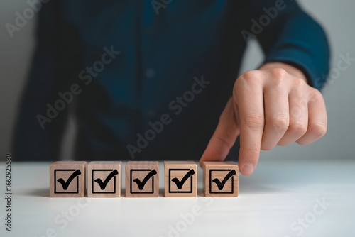 A person's hand touching a wooden block with a check mark on it amongst other similar blocks