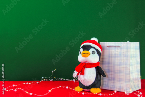 A stuffed penguin toy stands with a gift bag