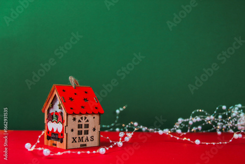 Christmas wooden house with red roof decorated with white bead garland