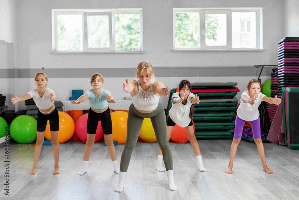 Obraz premium Group of girls exercising with female coach