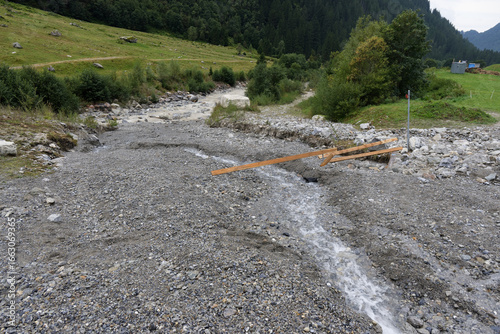Rockslide in river with broken wooden riverbank
