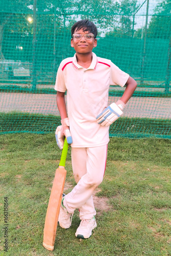Young boy cricketer smiling and posing with bat during practice session