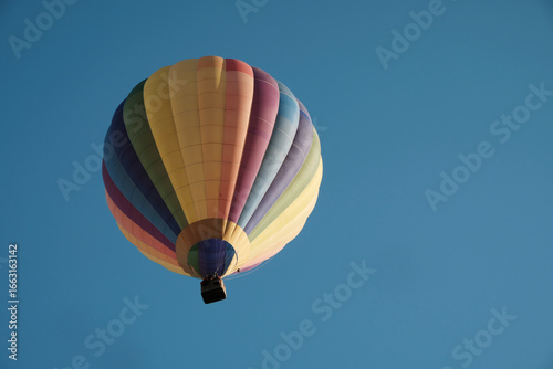 Colorful hot air balloon in flight against the sky. Hot air balloons are aircraft that obtain their lift by heating a large envelope of air above ambient temperature. Real photography, not AI.