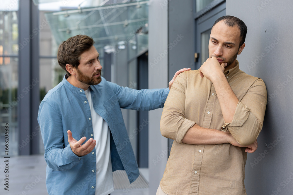 Murais de parede Two men discussing with concern and empathy beside a modern building