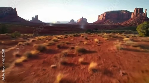 Monument Valley Landscape: A sweeping vista of Monument Valley's iconic mesas and buttes under a clear blue sky, capturing the vastness and raw beauty of the American Southwest.