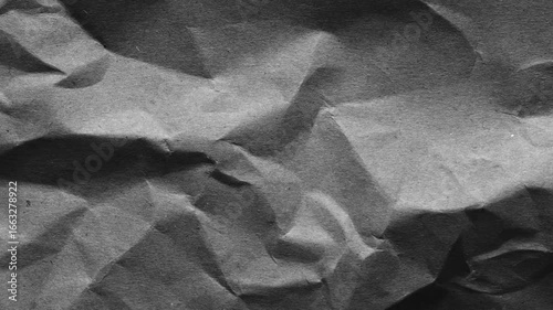 Dark wrinkled paper texture with aged grunge surface. Perfect for use as background, distressed overlay, retro wallpaper, or abstract design element in creative projects.