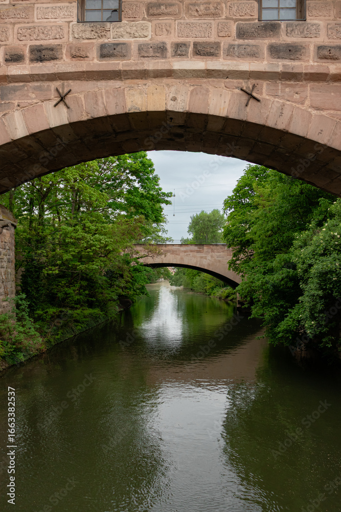 Fototapeta premium Hallertor Bridge (Hallertorbrucke) an arch bridge over the Pegnitz River on Nuremberg's Old Town's west side viewed from Kettensteg pedestrian bridge