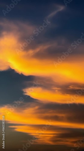 Vertical timelapse 9:16 of glowing sunset clouds moving fast across the sky, cinematic light.