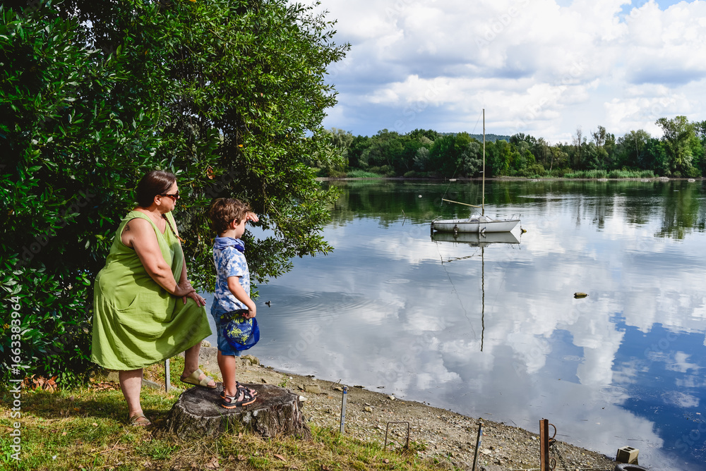 Obraz premium Mum and son enjoy a day by the tranquil lakeside in summer