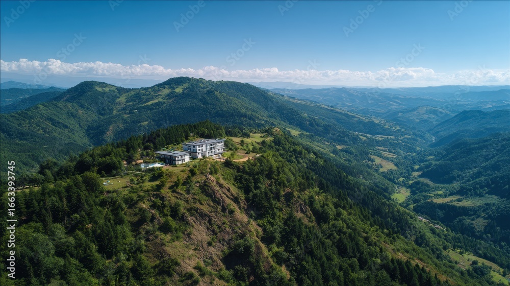 Obraz premium Stunning aerial view of a mountain lodge surrounded by lush green hills in the daytime