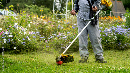 Man with grass trimmer mowing lawn