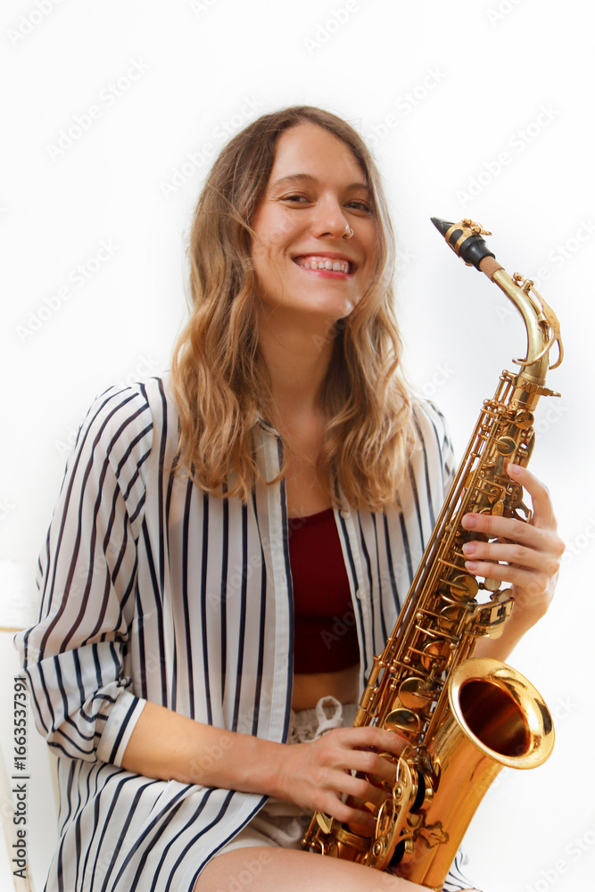 Fototapeta premium Smiling saxophonist playing her saxophone on white background