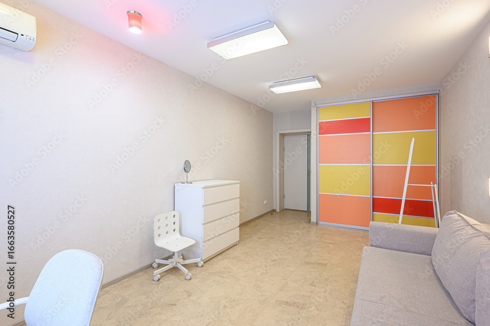 Fototapeta premium Bright, clean room with a gray sofa, white dresser, chair, and colorful sliding door wardrobe