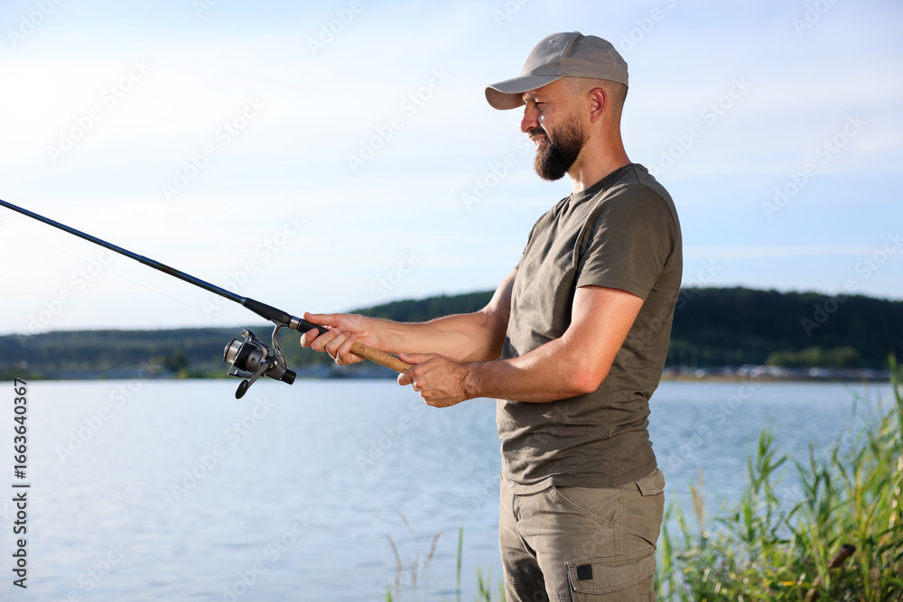 Fisherman with rod fishing near lake at summer Fisherman with rod fishing near lake at summer