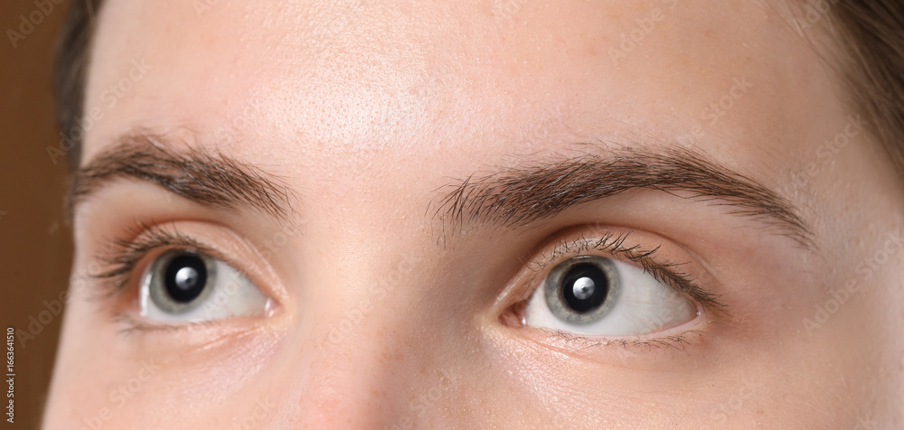 Naklejka premium Young woman with beautiful eyebrows on brown background, closeup
