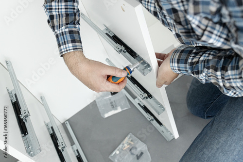 Close up of a Man Assembling a drawer slider Furniture using a screwdriver