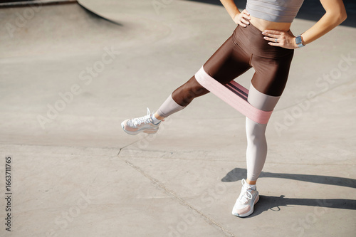 Cropped view of sporty woman doing exercises with resistance band
