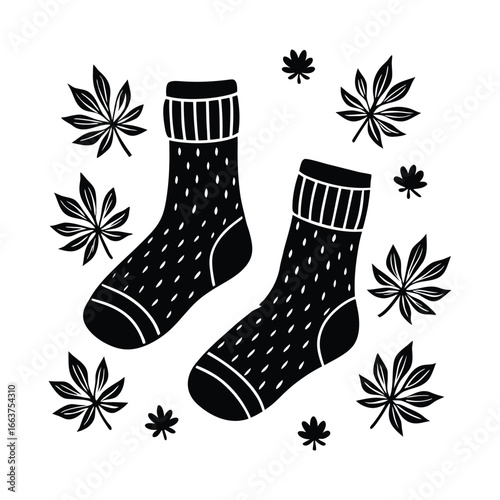 Cozy black and white socks surrounded by autumn leaves
