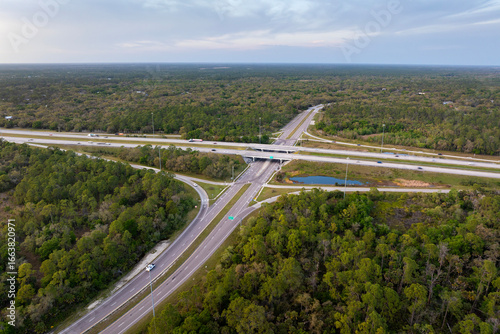 Wide multilane highway crossroads in Florida, USA with fast driving cars at sunset. Above view of American transportation infrastructure