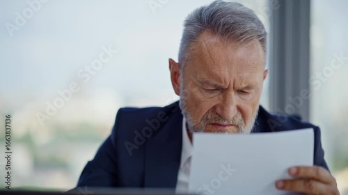 Stressed financier reading report at business office closeup. Elderly manager 