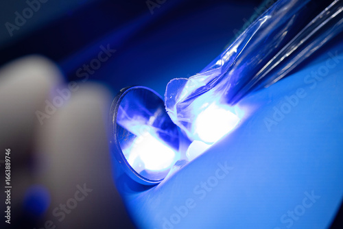 фотографія Close-up of isolated tooth illuminated by dental curing light with reflection in mirror