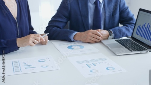 Photos Business auditors reviewing financial data, pointing at laptop charts and discussing documents during collaborative strategy session