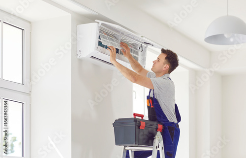 Konstfotografi Male worker from AC maintenance service, standing on ladder with toolbox, opens