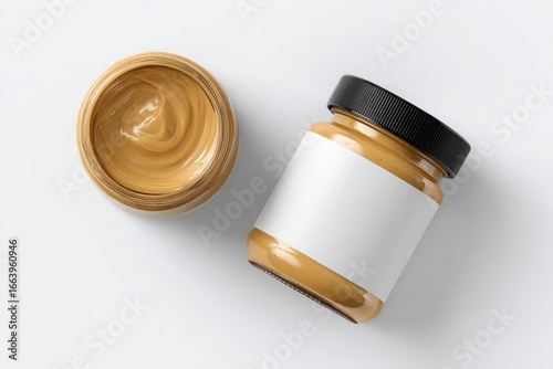 Two glass jars of light brown spread, one open, one closed, on a white background
