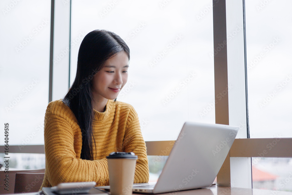 Obraz premium Young Asian Freelancer Working on Laptop in Modern Office Space