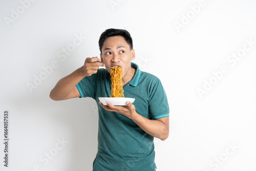 Asian man eats noodles with enthusiasm, capturing a moment of joy and enjoyment during a meal.