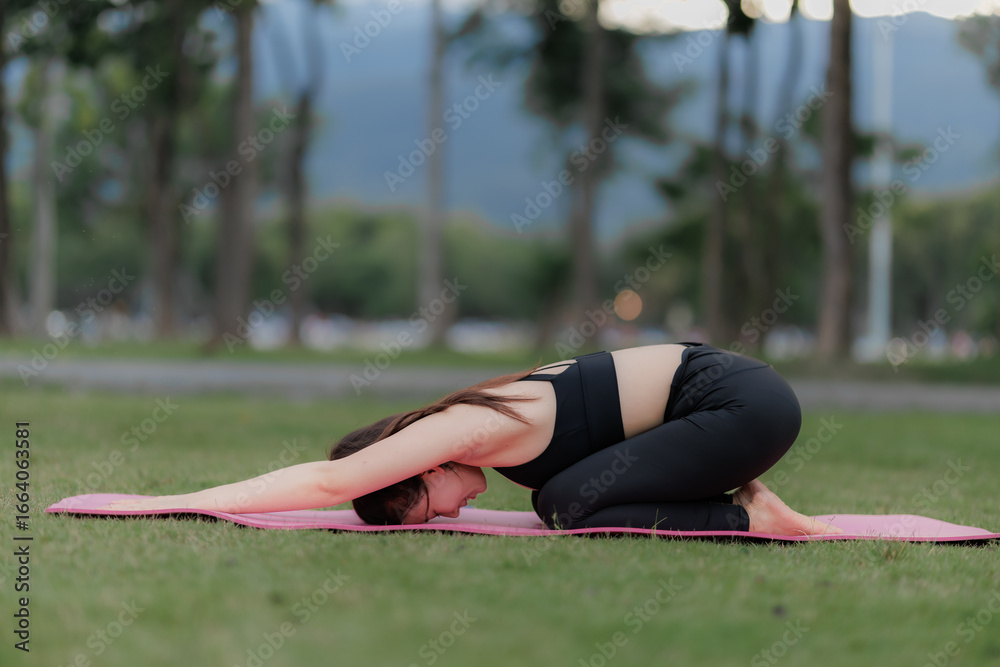 Fototapeta premium Serene yoga practice in the evening, Asian woman in work attire turned activewear, embracing peace and health.