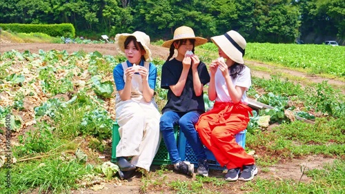 夏の高原で麦わら帽子をかぶった日本人の女の子たちが白いおにぎりを持って座る